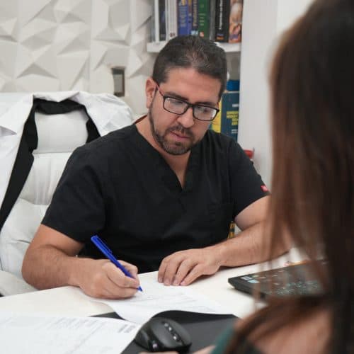 Dr. Santiago López Vega revisando el caso de una paciente en consulta.